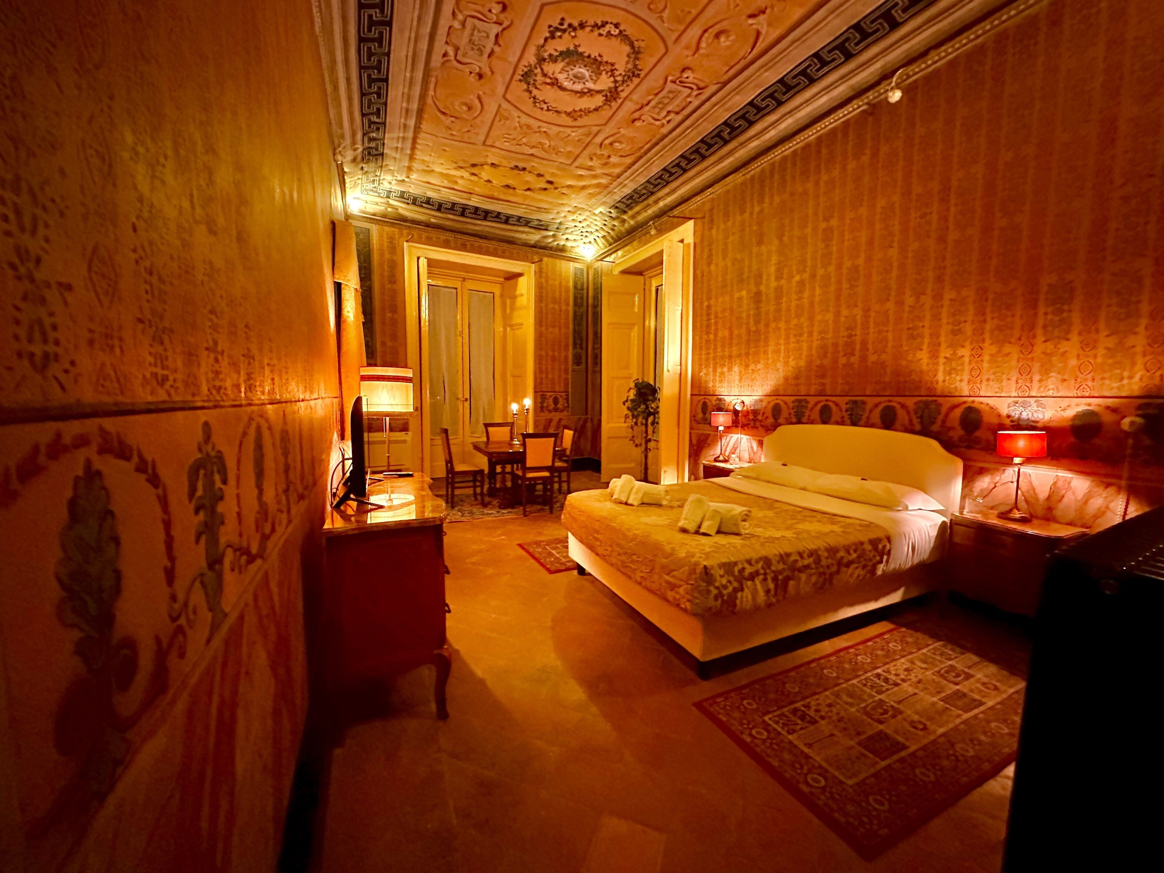 Une chambre d’hôtel avec un grand lit, un bureau avec une lampe, une chaise et une table à manger avec des chaises.