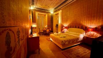 Une chambre d’hôtel avec un grand lit, un bureau avec une lampe, une chaise et une table à manger avec des chaises.