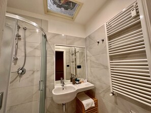 Un baño moderno con ducha de vidrio, tocador con lavamanos y un perchero para toallas.