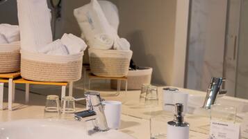 A modern bathroom with a large sink, two towel dispensers, and a glass shower enclosure.