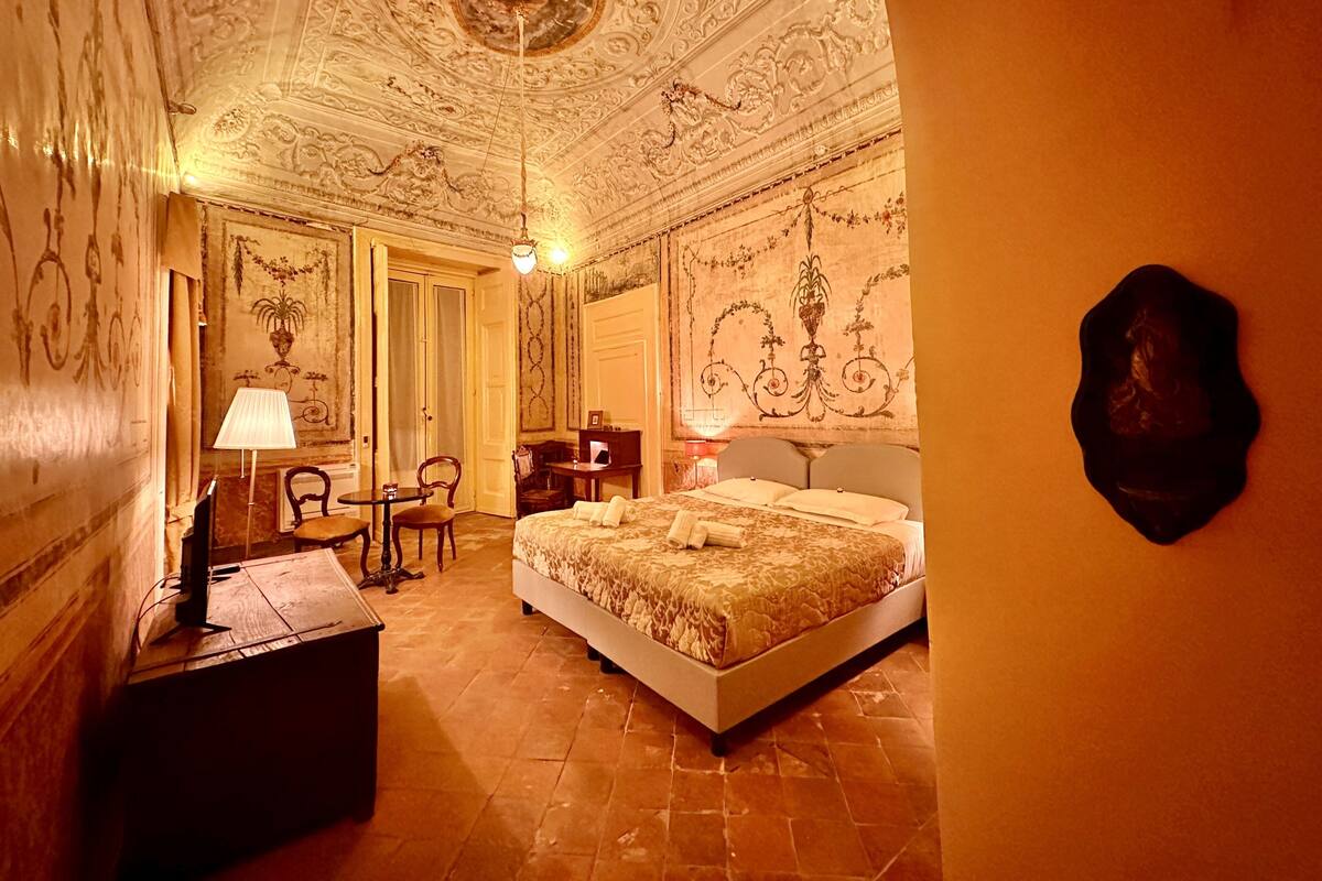 Ein Zimmer mit einem Bett, einem Schreibtisch, einem Sessel und einer Lampe.