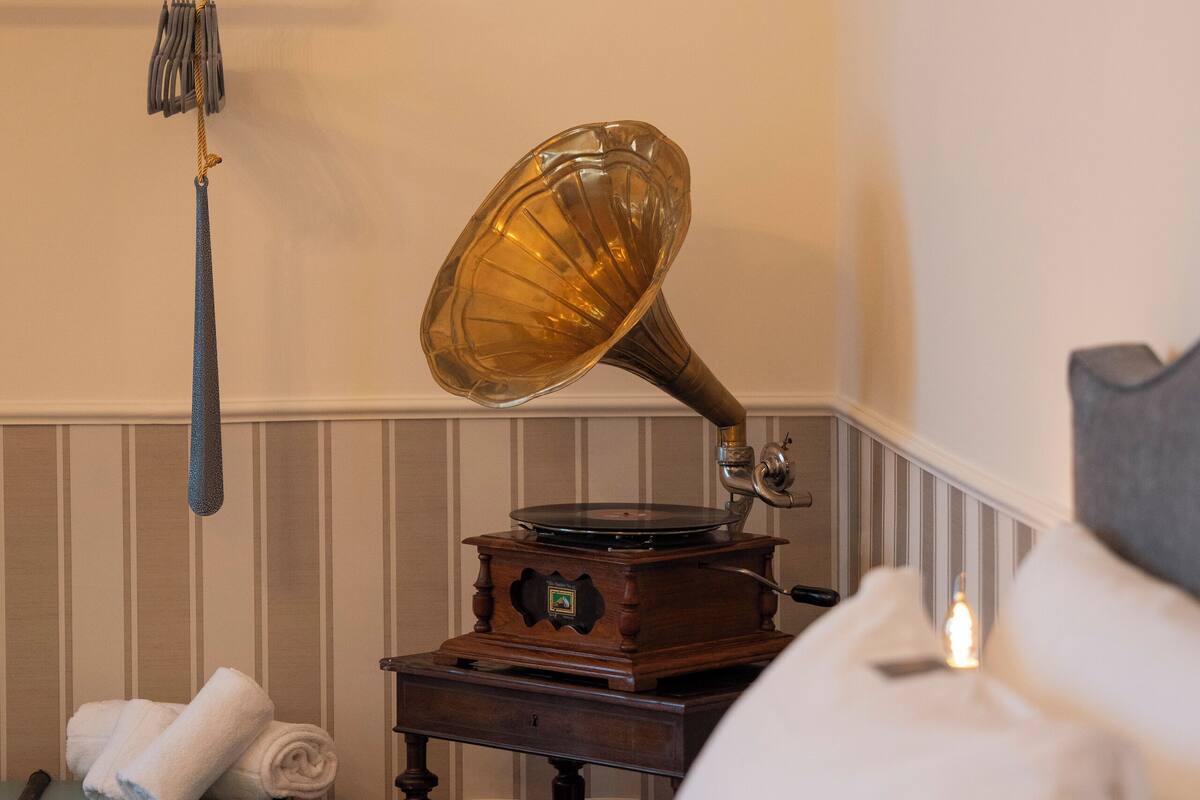 Ein Zimmer mit einem alten Grammophon, einem kleinen Tisch und einem Koffer.