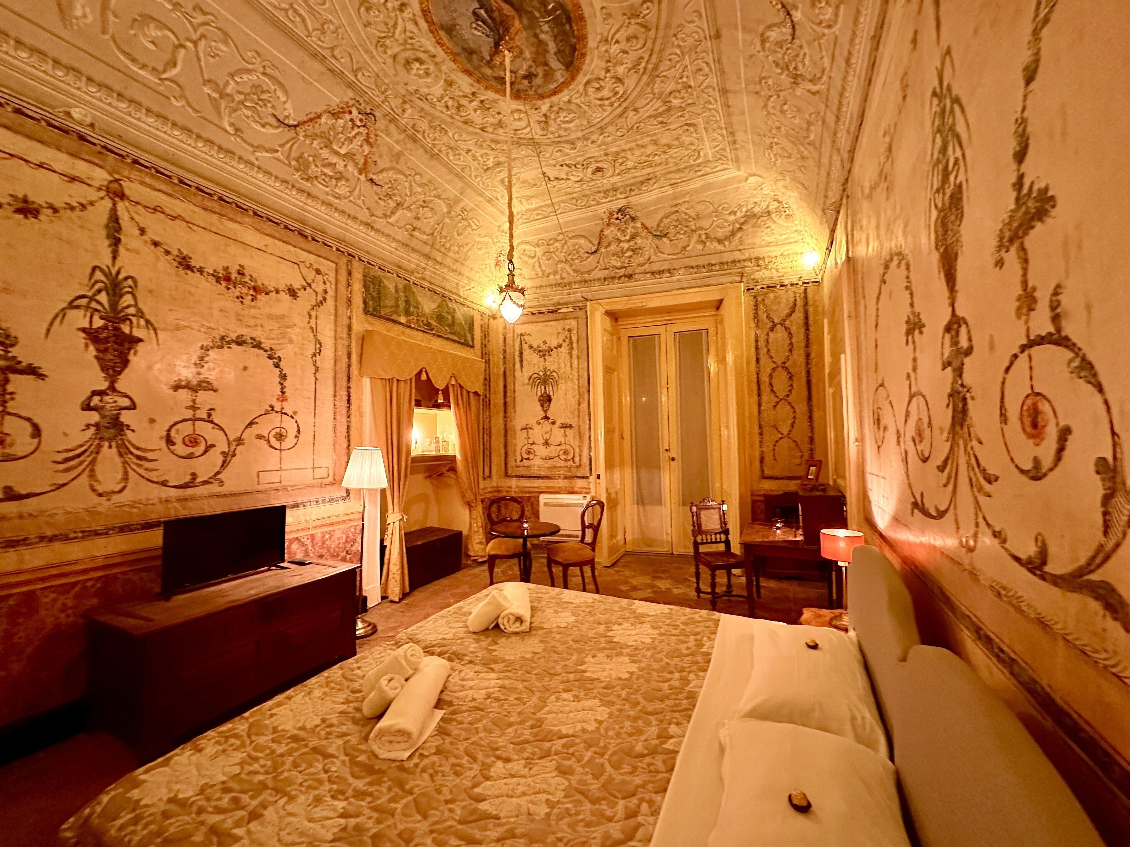 Une chambre avec un grand lit, un bureau, une chaise et une lampe.