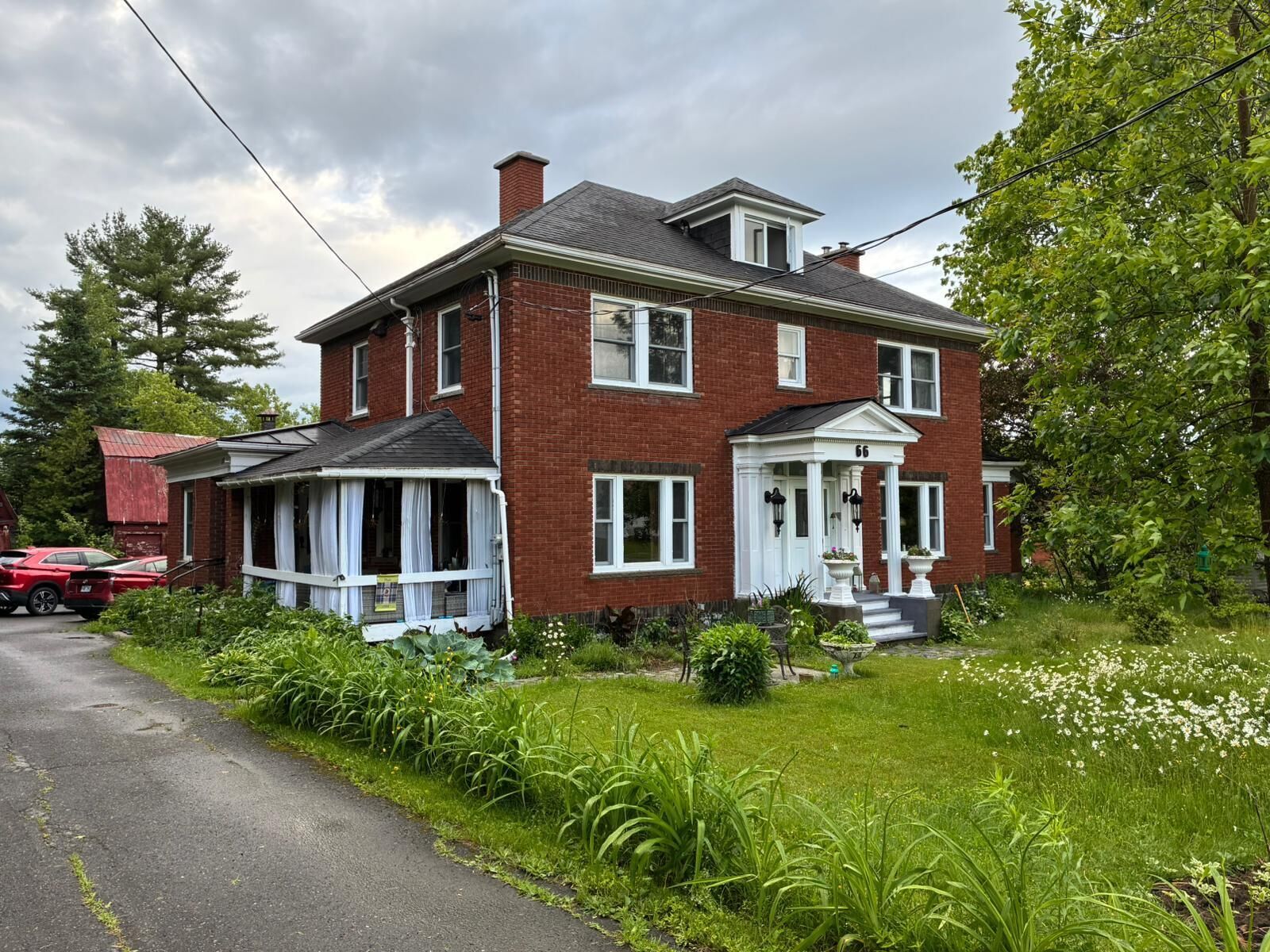 A two-story brick house with a front porch, a garage, and a driveway.