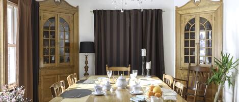 A dining room with a large wooden table set for a meal, surrounded by chairs.