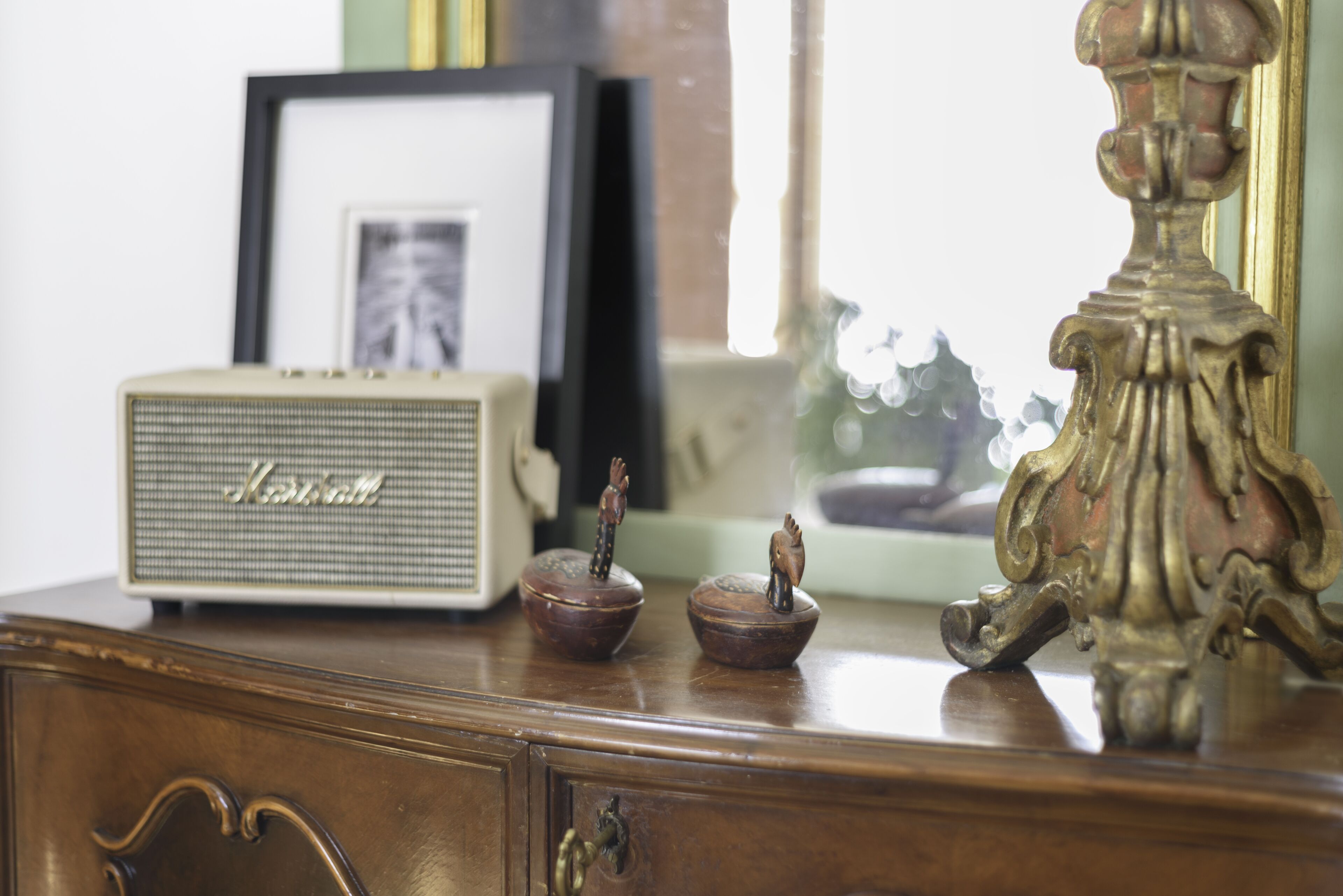 A vintage radio, a framed picture, and decorative items on a wooden dresser.