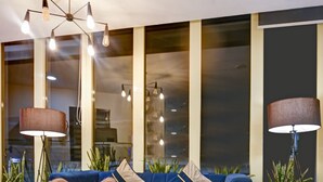 A modern lobby with a blue sofa, a round wooden table, and floor lamps. - Gallivanto Inn (New Delhi)