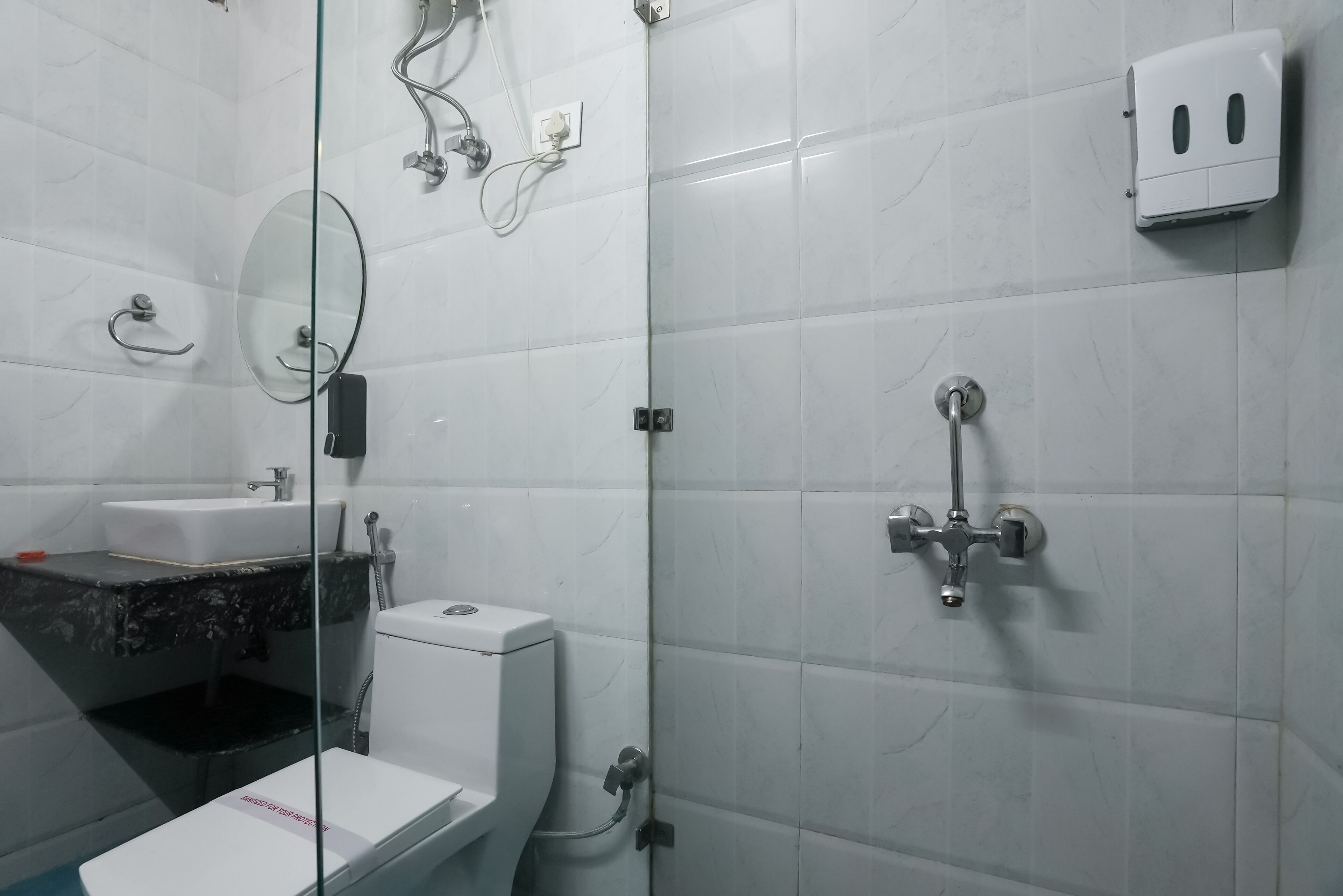 A modern bathroom with a glass shower enclosure, a toilet, and a sink with a marble countertop.
