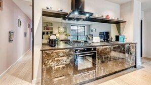 Una cocina moderna con una isla central, horno empotrado y una campana extractora grande.