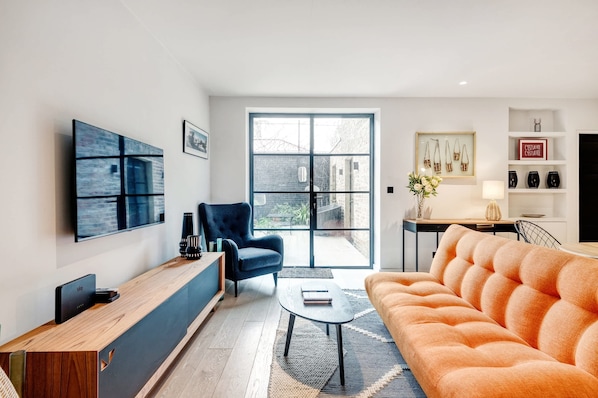 Un salon moderne avec un canapé, un fauteuil, une table basse et un téléviseur.