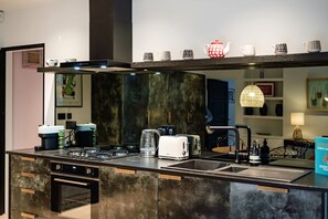 A modern kitchen with a built-in oven, a coffee machine, a toaster, and a sink.