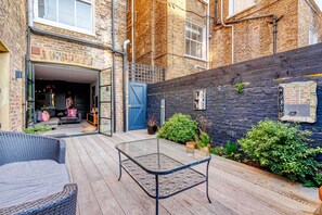 A courtyard with a glass table, wicker furniture, and potted plants. - Notting Hill 2 Bed with Sauna - by Out of Office Lifestyle (London)