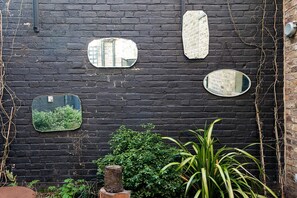 Un mur en briques noires orné de quatre miroirs de formes et de tailles différentes.