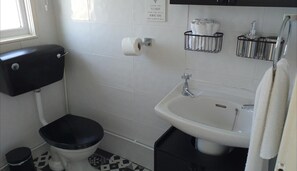 A small bathroom with a toilet, sink, and a toilet paper holder. - 2 Bed Chalet Sleeps 4- Parking, Garden, Near Beach (Great Yarmouth)