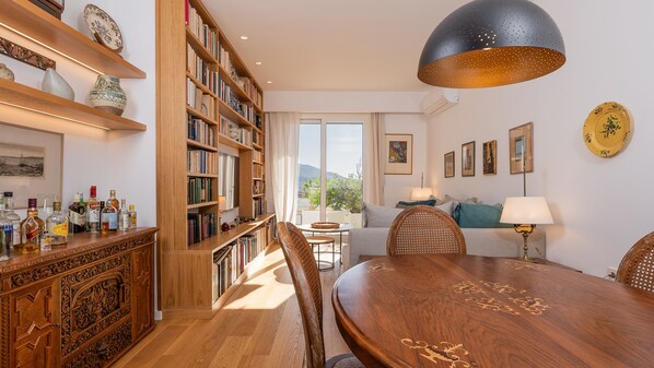 Amplia sala de estar con una mesa de comedor de madera, una estantería grande y vistas al exterior a través de un ventanal.