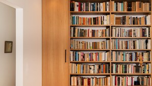 Een grote houten boekenkast vol boeken, een houten vloer en een witte muur.