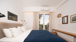 Hotelkamer met een bed, nachtkastje, een wandlamp, een ingelijst schilderij en een raam met gordijnen.