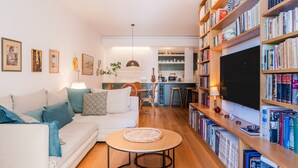 Een gezellige woonkamer met een bank, een ronde salontafel en een boekenkast vol boeken.