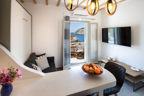 A modern living room with a balcony, a flat-screen TV, and a fruit bowl on the table.