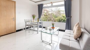 Een moderne woonkamer met een glazen salontafel, een bank en een eethoek met stoelen en een kleine tafel.