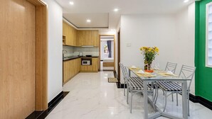 Een moderne keuken met houten kastjes en een eethoek met een glazen tafel en metalen stoelen.