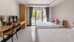 Een hotelkamer met twee bedden, een houten bureau, een televisie en een balkon met gordijnen.