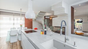 Una cucina moderna con isola centrale, elettrodomestici integrati e una scala in vetro.