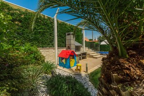 Children can play safely in this enclosed area with a playhouse and lush greenery.
