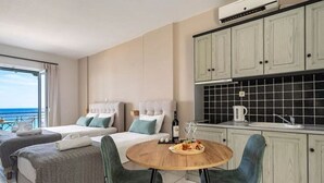 A hotel room with two beds, a dining table with chairs, a kitchen area, and a view of the sea. - Apartment In A Hotel 'Sunset Triple 2' with Sea View, Wi-Fi and Air Conditioning (Lefkada)