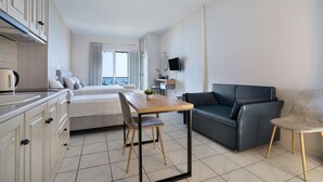 A modern hotel room with a bed, a dining table, a sofa, and a TV. - Studio Apartment 'Sunset Triple 1' with Sea View, Wi-Fi and Air Conditioning (LEFKADA)