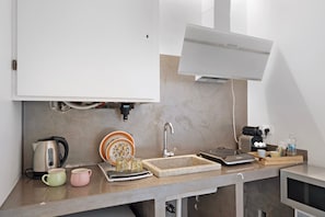 Eine Küche mit integriertem Mikrowellenherd, Wasserkocher, Spüle und Kaffeemaschine.