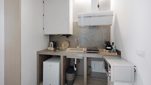 A compact kitchenette with a built-in microwave, a small sink, and a stove. - 'Ama' Apartment with Balcony, Wi-Fi, and Air Conditioning (Albenga)