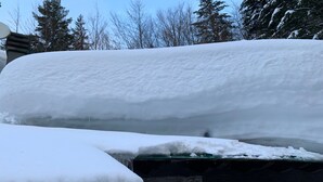 Un toit recouvert de neige, avec des glaçons qui y pendent.