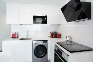 A compact kitchen with a washing machine, a microwave, a toaster, and a coffee maker.