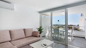 Ein modernes Wohnzimmer mit einer Couch, einem Couchtisch und einer Schiebeglastür, die auf eine Terrasse im Freien mit Blick gelangt.