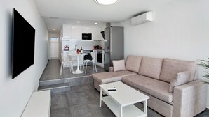 Ein modernes Wohnzimmer mit einer Couch, einem Couchtisch und einem an der Wand befestigten Fernseher.