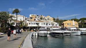 A marina with boats docked, a pedestrian walkway, and buildings with signage. - Villa 'Casa Kasima' with Private Pool, Wi-Fi and Air Conditioning (Calahonda)