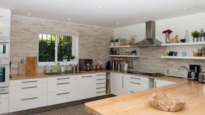 A modern kitchen with white cabinetry, a large island, and a window overlooking greenery. - Villa 'Casa Kasima' with Private Pool, Wi-Fi and Air Conditioning (Calahonda)