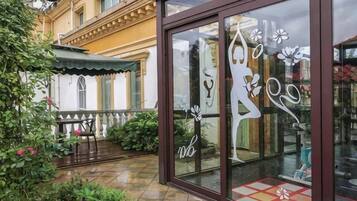 A storefront with a glass facade, a metal awning, and a bench outside.