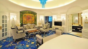 A hotel room with a large bed, two armchairs, a coffee table, a TV, and a decorative wall piece. - Nanhu Garden Hotel (Guiyang)