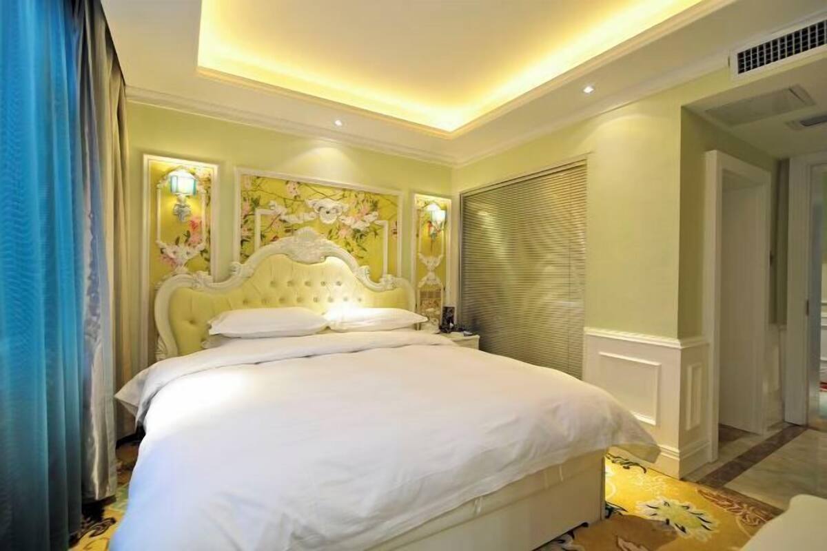 Ein Hotelzimmer mit einem großen Bett, einer Kristalllüster und einer Wanddekoration mit floralem Muster.
