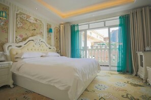Une chambre d’hôtel avec un grand lit, une table de chevet, une commode et une vue sur l’extérieur grâce à un balcon agrémenté de rideaux verts.