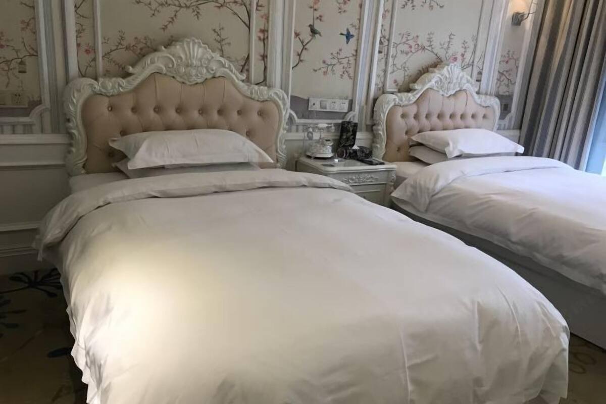 Ein Hotelzimmer mit zwei Betten, jeweils mit einem gesteppten Kopfteil und weißer Bettwäsche.