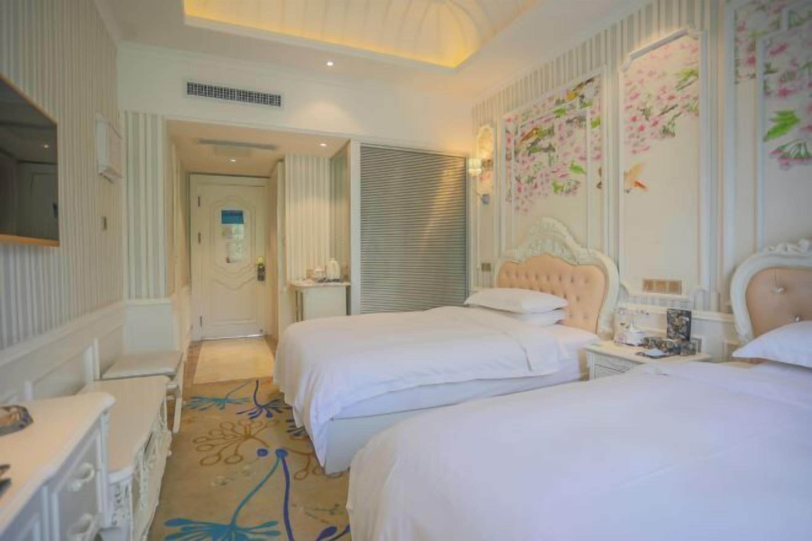 A hotel room with two beds, a bedside table, a mirror, and a decorative wall.