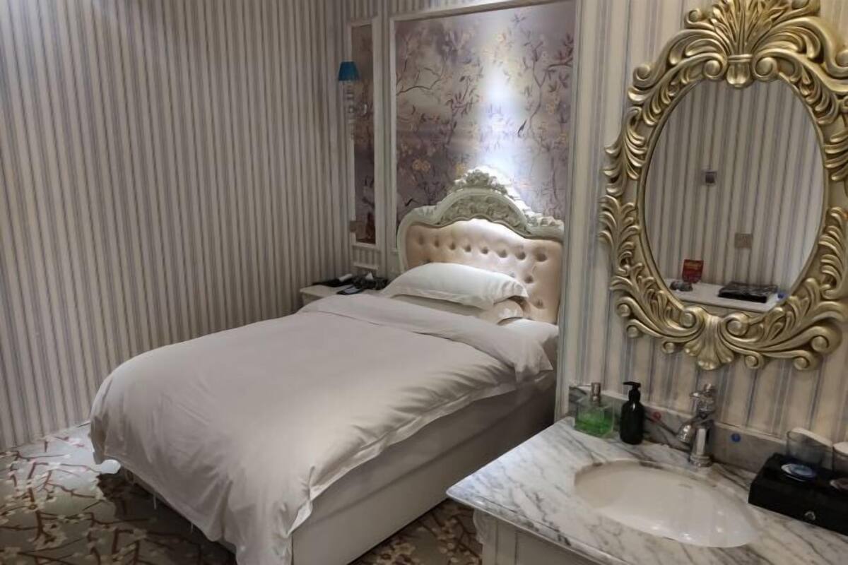 Ein Schlafzimmer mit Bett, Schminktisch mit Spiegel und einem Badezimmer mit Waschbecken.