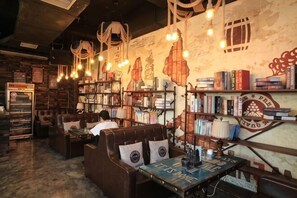 Une librairie chaleureuse, avec des étagères remplies de livres, des coins lecture et des lampes suspendues.