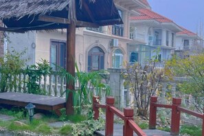Un immeuble à plusieurs étages doté d’un balcon, d’une terrasse en bois et d’une rambarde rouge.