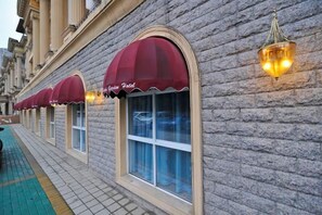 A row of hotel rooms with arched windows and red awnings.
