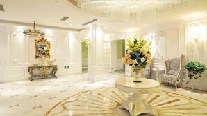A luxurious lobby with a grand chandelier, ornate columns, and a central round table with a floral arrangement. - Nanhu Garden Hotel (Guiyang)