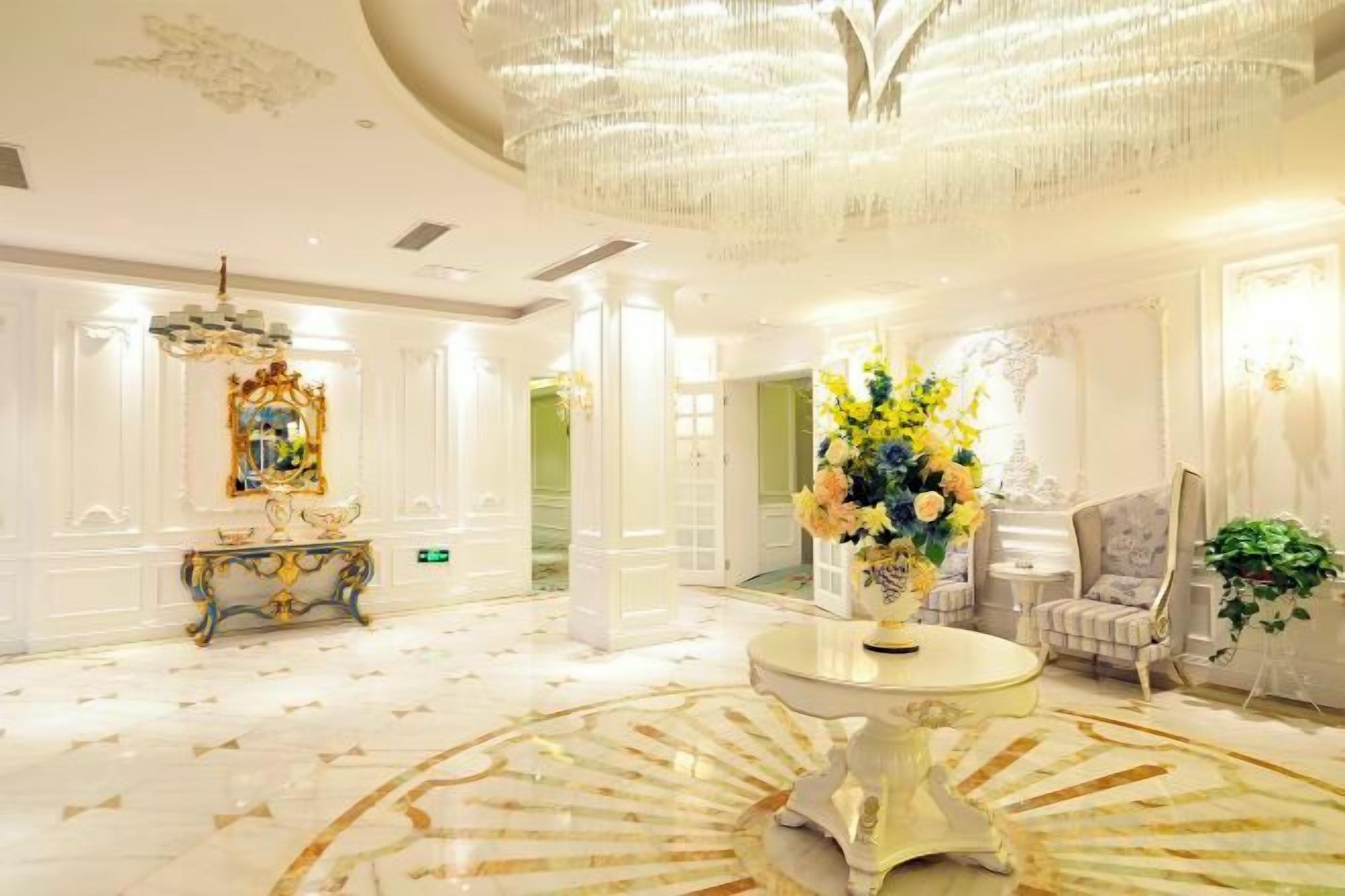 Eine luxuriöse Lobby mit einem prächtigen Kronleuchter, einem runden Marmortisch und einer Blumenkomposition.
